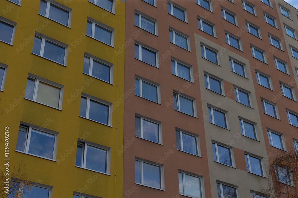 A vibrant and colorful facade of an apartment building, showcasing an array of multiple windows prominently A vibrant and colorful facade of an apartment building, showcasing an array of multiple windows prominently