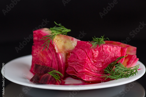 pickled cabbage with beets and carrots, in a plate, isolated on black background