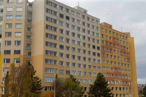 Two multistorey urban residential buildings with varying faades and trees photo