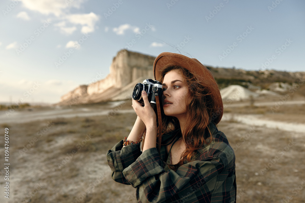 Stylish woman in plaid shirt and hat taking a picture with vintage camera outdoors Stylish woman in plaid shirt and hat taking a picture with vintage camera outdoors