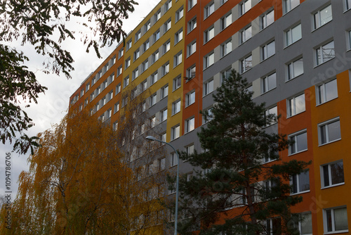 An apartment building featuring a vibrant and colorful facade, complemented by trees in the background