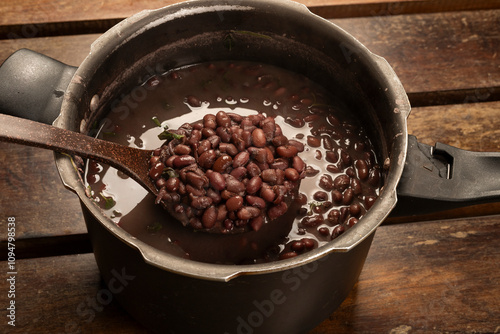 фотографія Black Beans Cooked in the pressure cooker with a bean ladle on a wooden desk