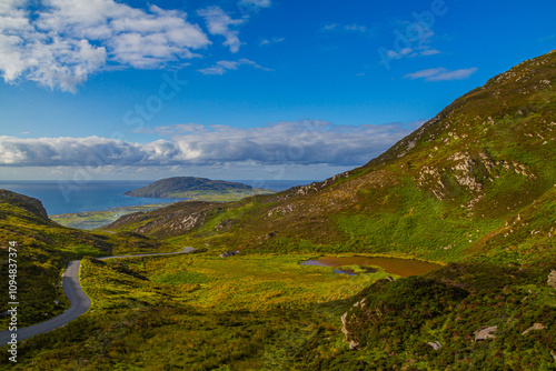 a green meadow with mountains against a blue sky