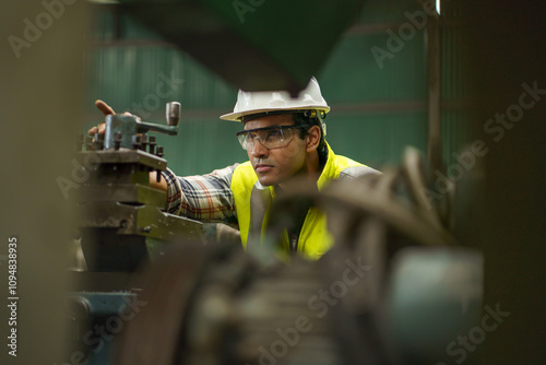 industrial Engineer indian man control lathe machine in industry manufacturing large factory . asian india labor worker male in hard hat and goggles working metal work in workplace . banner copy space photo