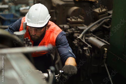 industry Engineer using wrench to maintenance big machine in Factory . worker or labor beard man employee wearing uniform in manufacturing