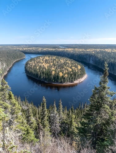 Aerial view of a picturesque river curving around an island filled with lush green trees. The bright blue sky and autumn foliage add vibrant colors to this serene landscape. photo