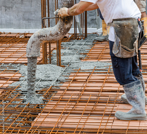 builders in orange shirt pouring concrete works on the construction site