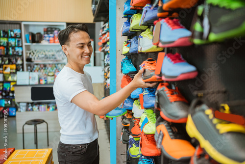 Wallpaper Mural smiling asian salesman arranging athletic shoes in the display Torontodigital.ca