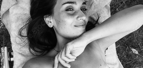giovane donna su asciugamano giallo all’aperto, espressione serena immersa nella natura. photo
