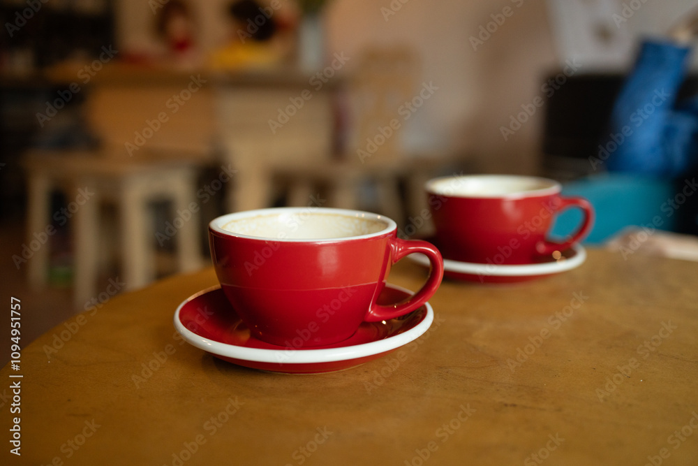 Two beautiful red cups of cappuccino with trendy heart shape latte art. Summer loft cafe background. Urban space. Drinking coffee on the terrace. High quality photo Two beautiful red cups of cappuccino with trendy heart shape latte art. Summer loft cafe background. Urban space. Drinking coffee on the terrace. High quality photo