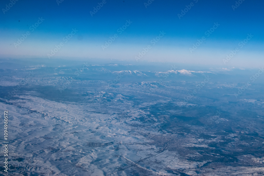Fototapeta premium view of mountains covered with snow from an airplane window, Cyprus