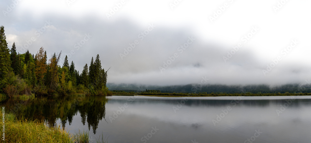 Fototapeta premium Early misty morning at autumn colored lake with cloudy sky fading to transparent. Vermillion Lake Banff 