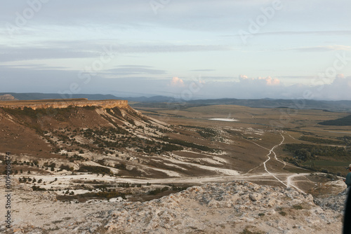 Mountain top view of valley and road in travel destination landscape with man standing and admiring scenic beauty