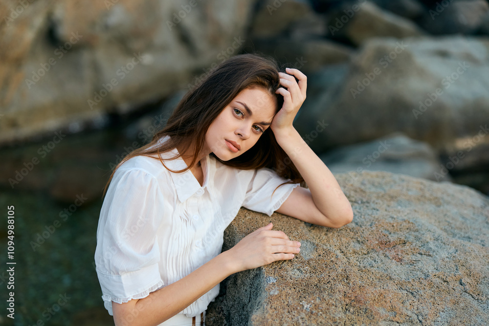 Serene young woman enjoying the ocean view from a rocky perch Serene young woman enjoying the ocean view from a rocky perch