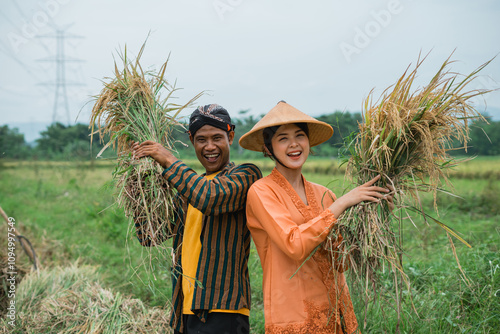 Joyful farmers proudly hold fresh rice in the vibrant fields, basking in the summer sun