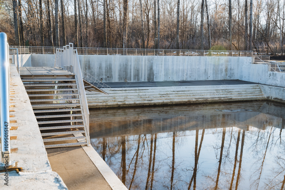 Fototapeta premium A vast expanse of water surrounded by lush trees that are beautifully mirrored in its tranquil surface, creating a stunning natural scene that showcases the beauty of the landscape