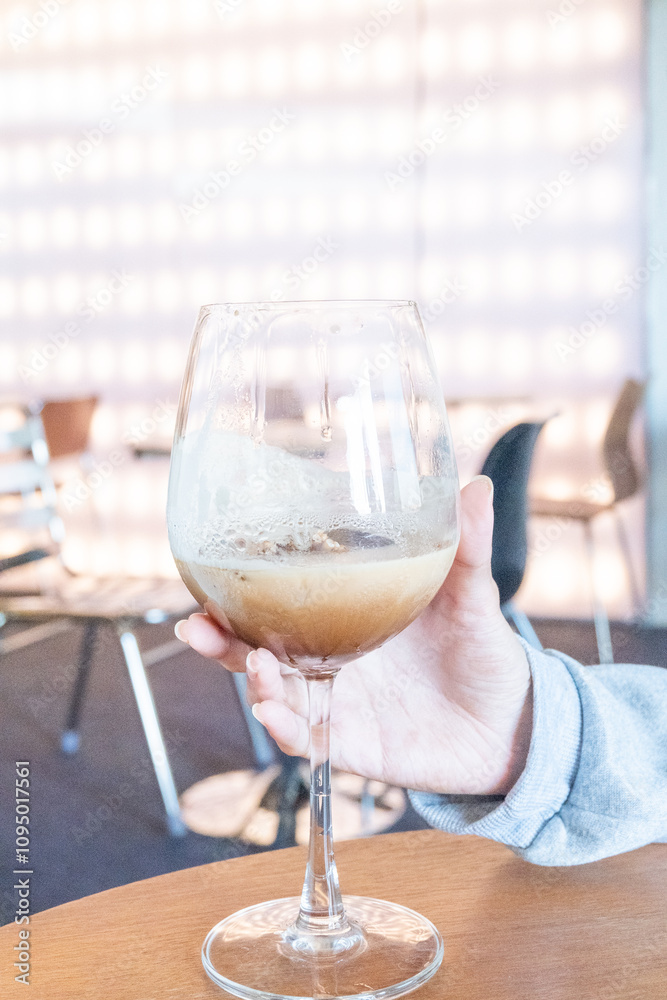 Obraz premium Young girl holding glass of Cold Mocktail on table,female hand swirling red wine in wine glass,Friends cheering with wineglasses.