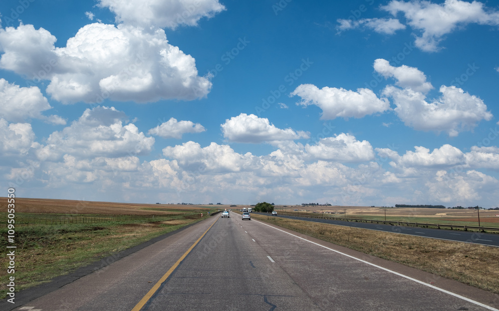 Highway in South African countryside. Grassy fields and farmland, blue sky with fluffy clouds Highway in South African countryside. Grassy fields and farmland, blue sky with fluffy clouds