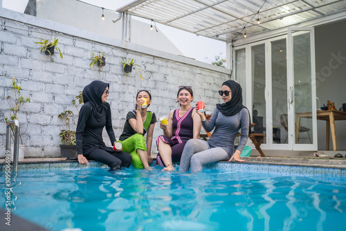 Four friends in colorful swimwear are joyfully enjoying a sunny day by the poolside