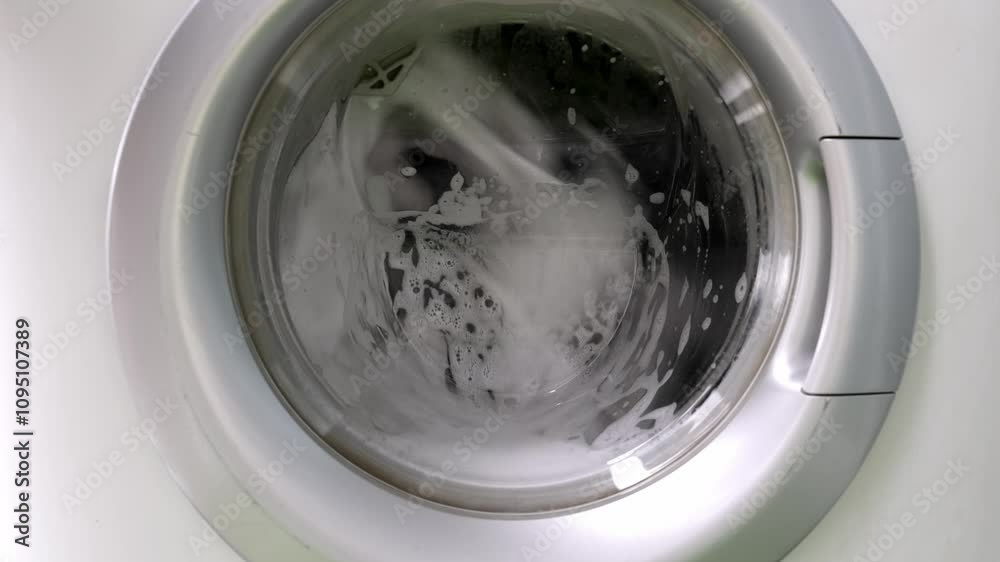 Close-up of clothes washing in a machine with foam. Concept of laundry, cleanliness, and modern household chores in daily life. Close-up of clothes washing in a machine with foam. Concept of laundry, cleanliness, and modern household chores in daily life.