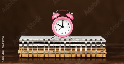 Alarm clock on a spiral notebooks, time management or save time banner, background