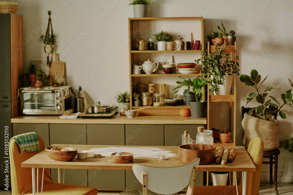 Modern kitchen with various plants and kitchenware displayed on shelves, and a wooden counter cluttered with baking ingredients and tools creating a cozy and inviting atmosphere Modern kitchen with various plants and kitchenware displayed on shelves, and a wooden counter cluttered with baking ingredients and tools creating a cozy and inviting atmosphere