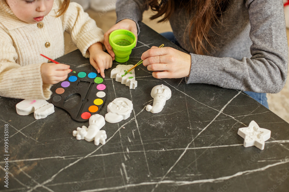Naklejka premium Child painting Christmas decorations at home with parent during holiday season