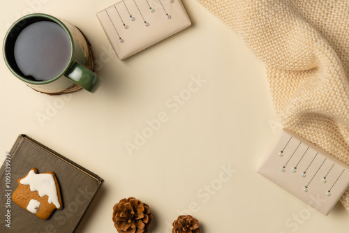 Christmas coziness composition with cup of tea, gingerbread, gift boxes and book on beige background. Flat lay, top view.