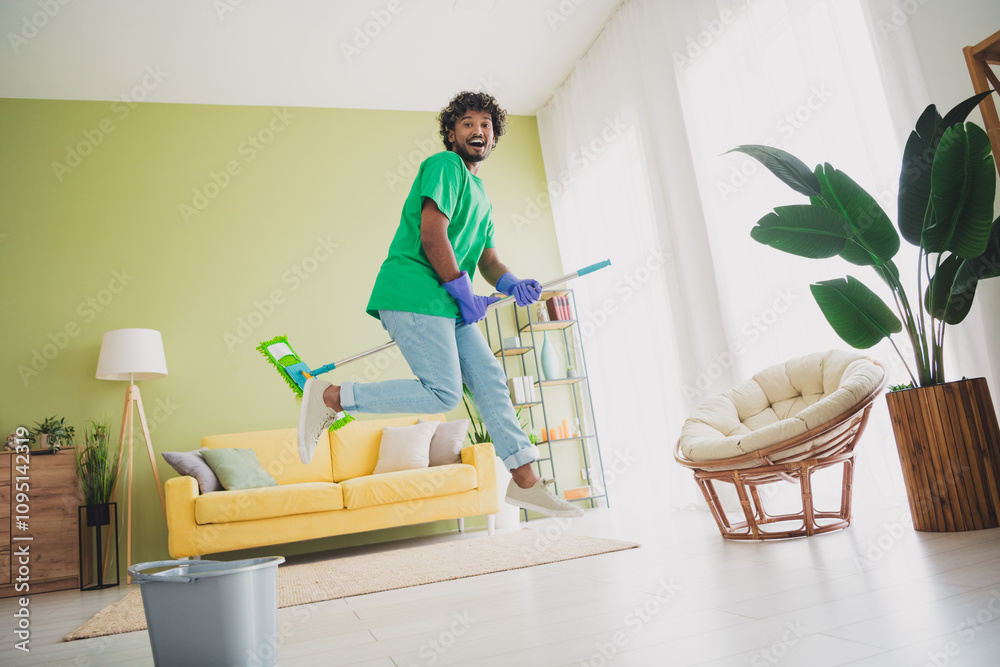 Full body portrait of nice young man jumping mop clean modern green interior flat indoors Full body portrait of nice young man jumping mop clean modern green interior flat indoors