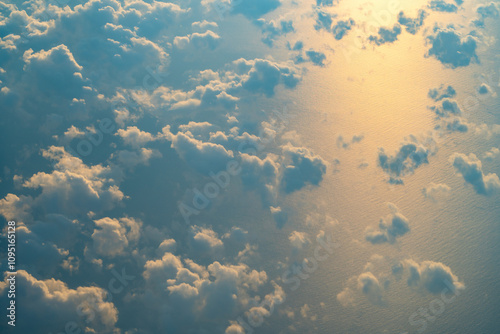 Clouds over a serene ocean reflecting the sunset glow, creating a tranquil view from above during late afternoon hours photo