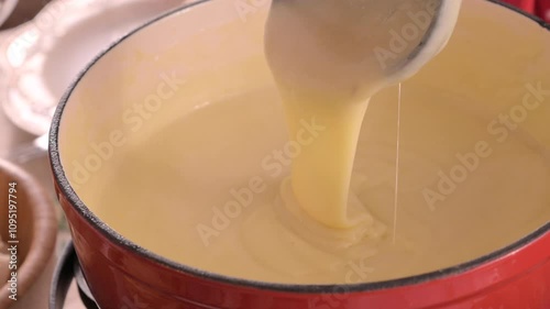 Cozy Swiss fondue setup with melted cheese, bread, pickles, and wine on a rustic table. advertising, social media campaigns, or food-related promotions. High quality 4k footage