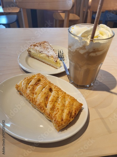A delicious-looking pastry, a slice of cake, and a creamy iced coffee, perfect for a cozy afternoon in a coffee shop. The image captures a moment of relaxation and indulgence.