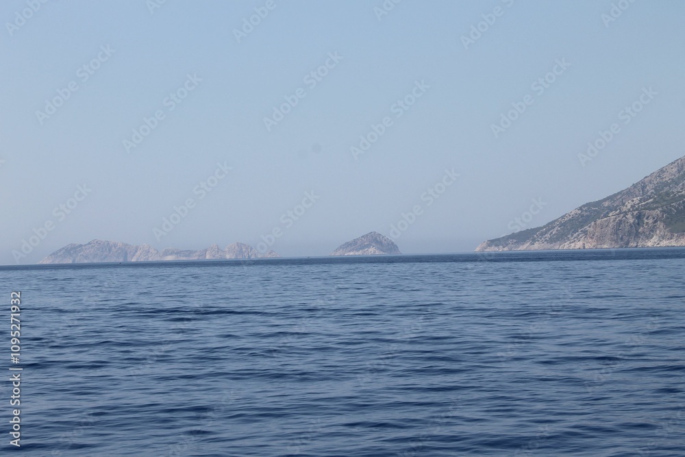 Scenic view of rocky coastline with clear blue waters and a boat Scenic view of rocky coastline with clear blue waters and a boat
