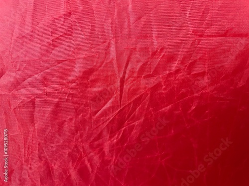 Red crumpled fabric. Texture as background. Uneven red surface.