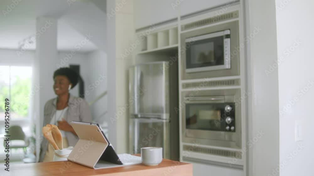 Lovely black woman with earbuds starting the day to work from home in the kitchen Lovely black woman with earbuds starting the day to work from home in the kitchen