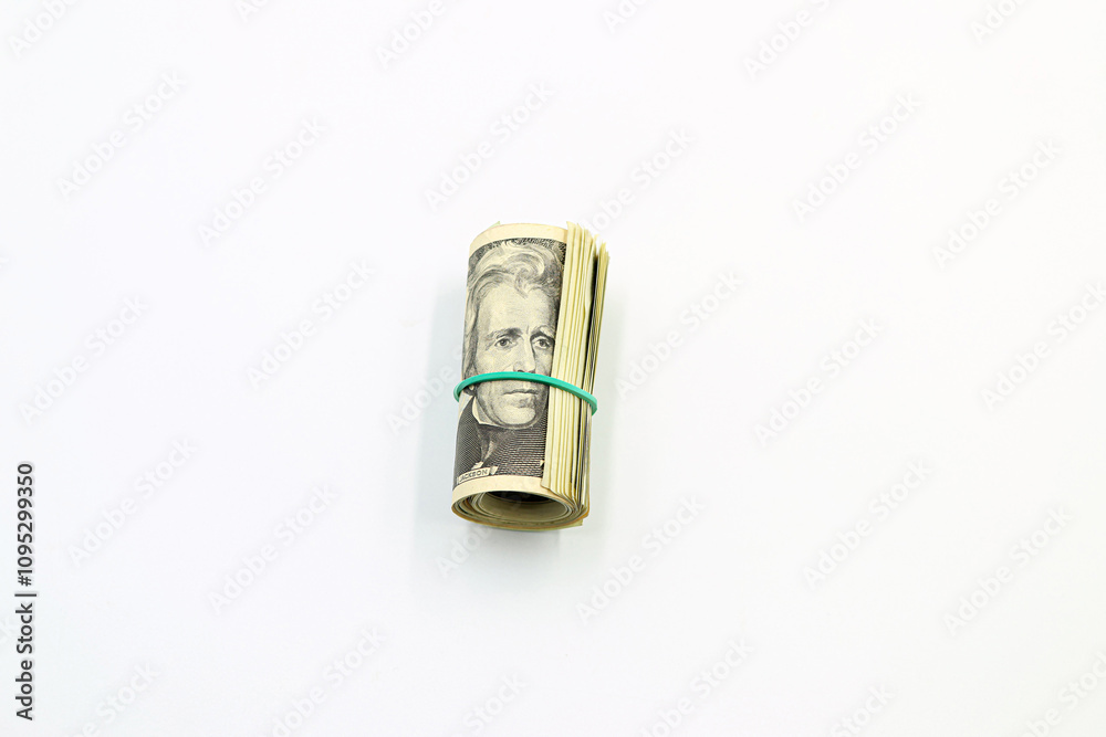 A bundle of American dollar bills surrounded by a green rubber band on a white background. A bundle of American dollar bills surrounded by a green rubber band on a white background.