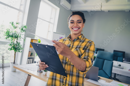 Photo of lovely young lady read report hold paperholder dressed yellow plaid shirt comfortable startup office loft room interior photo