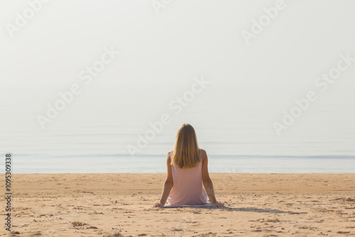 Photography Young adult woman sitting alone on sand and looking far away at sea beach in warm sunny summer day
