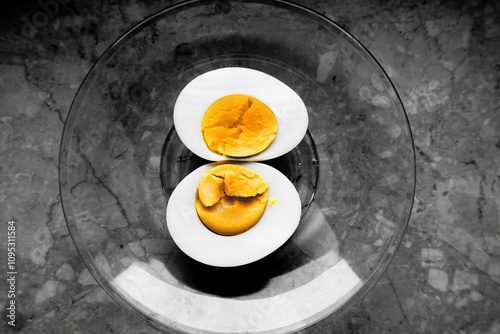 Yellow egg yolk on a glass plate on black and white background
