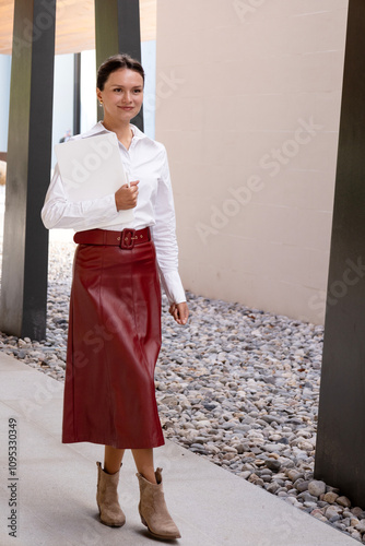 Business woman walking around an office center. Happy, symbolizing success. She is holding a white, clean tablet and a stylus. The concept of successful business development  photo