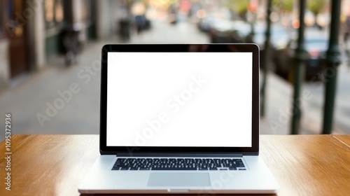 Laptop computer sits on wooden table outside a cafe