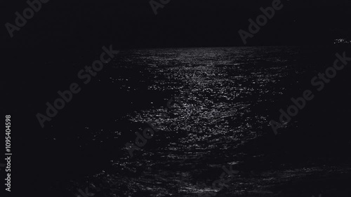 Waves at night under the moonlight. The moon’s reflection on the ocean at night.