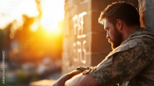 A melancholy soldier with a beard leans on a sun-kissed wall, his posture conveying deep thought and reflection, framed by a warm, glowing sunset backdrop. photo