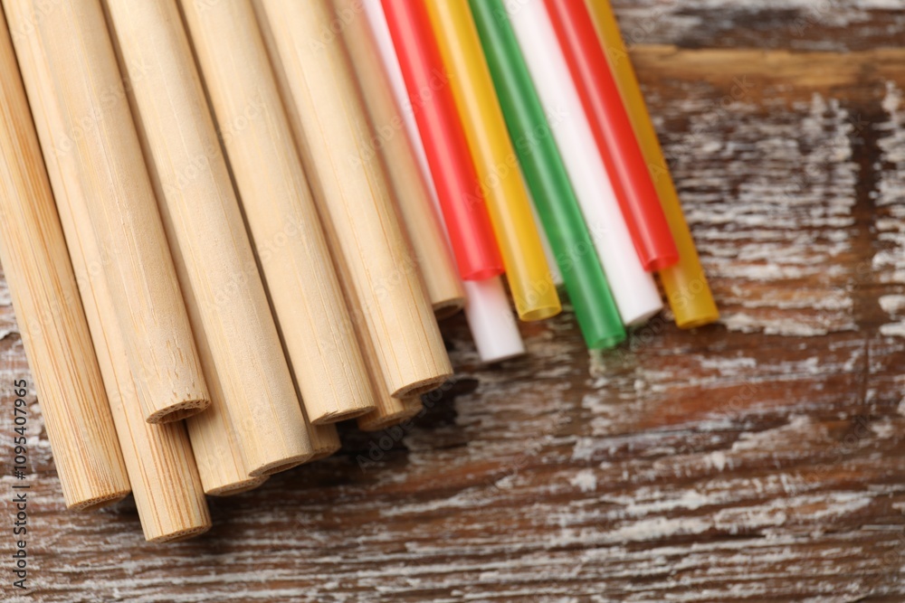 Different drinking straws on wooden table, closeup