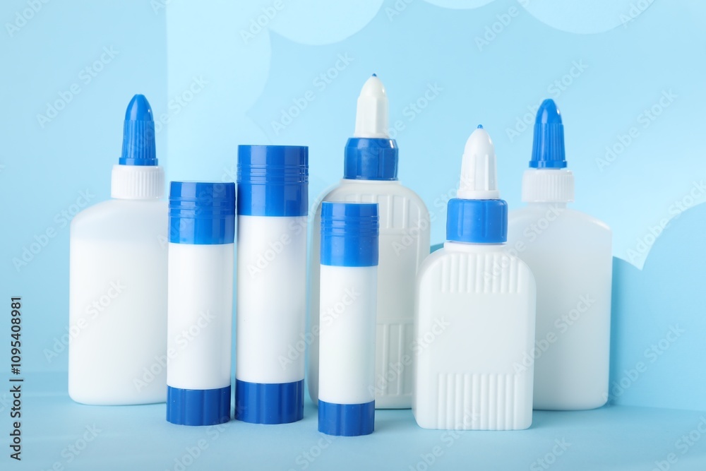 Bottles and sticks of glue on light blue background Bottles and sticks of glue on light blue background