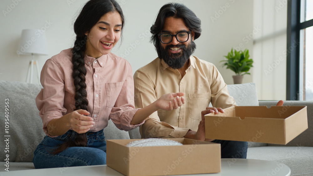 Happy couple customers receive parcel look inside box Arabian Indian man and woman open delivery excited husband and wife shopping online unbox purchase unpacking present make internet order buy goods Happy couple customers receive parcel look inside box Arabian Indian man and woman open delivery excited husband and wife shopping online unbox purchase unpacking present make internet order buy goods