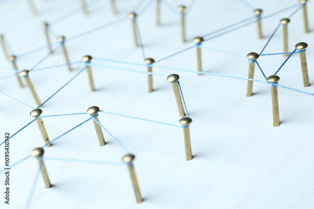Network connection. Nails linked together by thread on white table, closeup Network connection. Nails linked together by thread on white table, closeup
