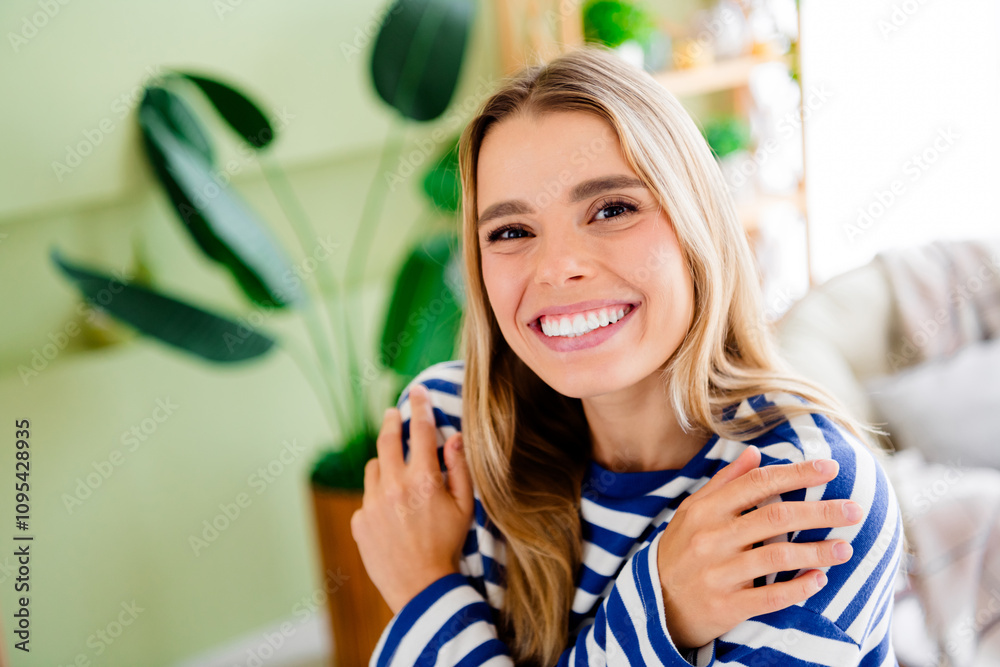 Fototapeta premium Photo of nice blonde young girl hugging self touch shoulder wear striped clothes enjoy modern cozy interior flat indoors