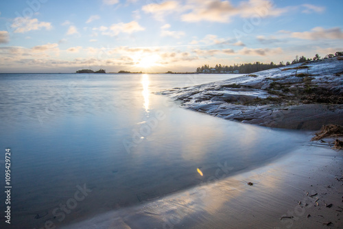Fototapeta Naklejka Na Ścianę i Meble -  Shore of a lake at sunrise. Landscape shot in the Narur in the morning. Forests lake and water at the beginning of winter or in autumn. Sweden, Scandinavia