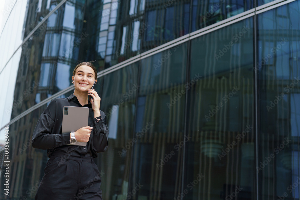 Professional individual engaging in a phone conversation while walking next to modern glass building Professional individual engaging in a phone conversation while walking next to modern glass building